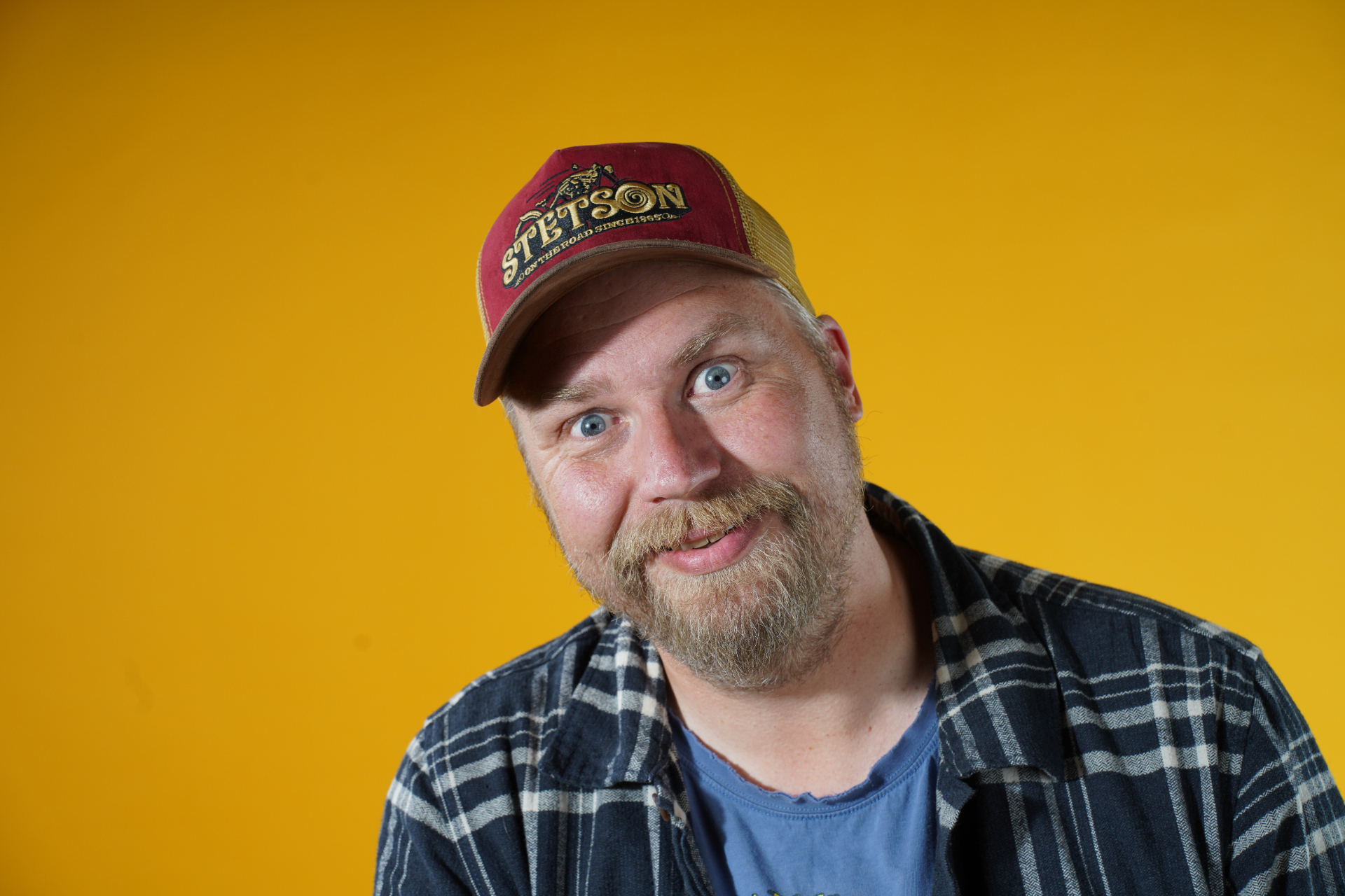 Portrett av Hroar Nordhaug med caps mot gul bakgrunn